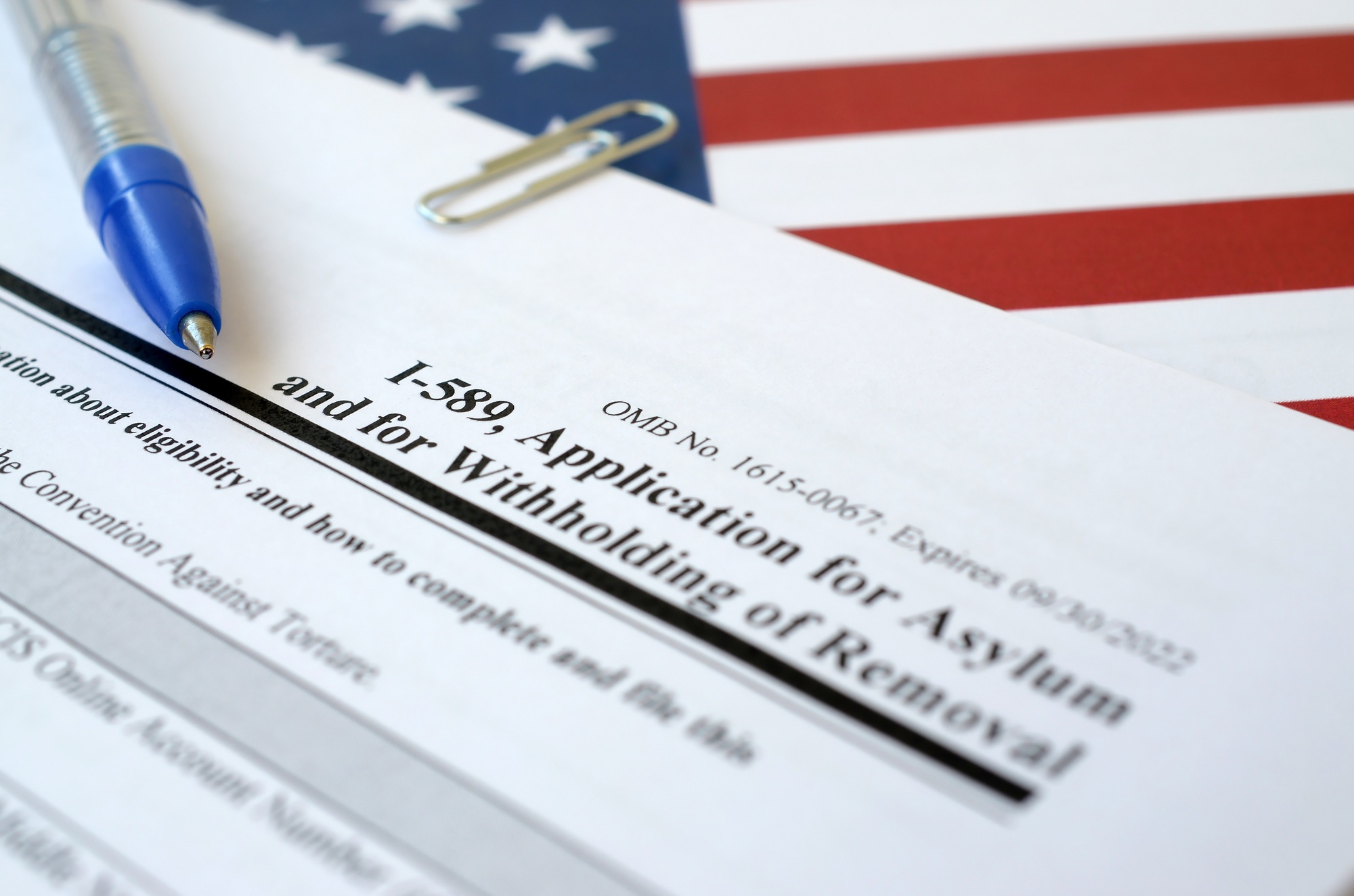 I-589 Application for asylum and for withholding of removal blank form lies on United States flag